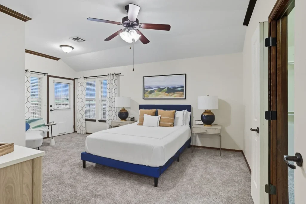 Bedroom with a blue bed frame, nightstands with lamps, a ceiling fan and windows