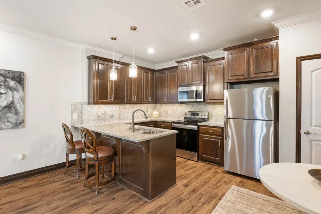 Kitchen with dark wood cabinets, stainless steel appliances and a breakfast bar with stools