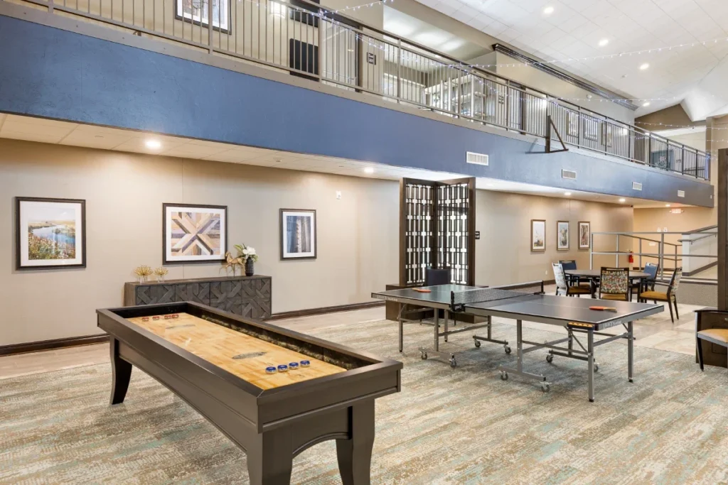 Multipurpose room with a shuffleboard table, ping-pong tables and a mezzanine balcony overhead