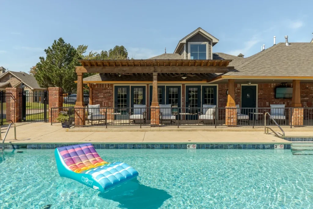 Swimming pool with a pool float in front of a covered brick pavilion with a pergola