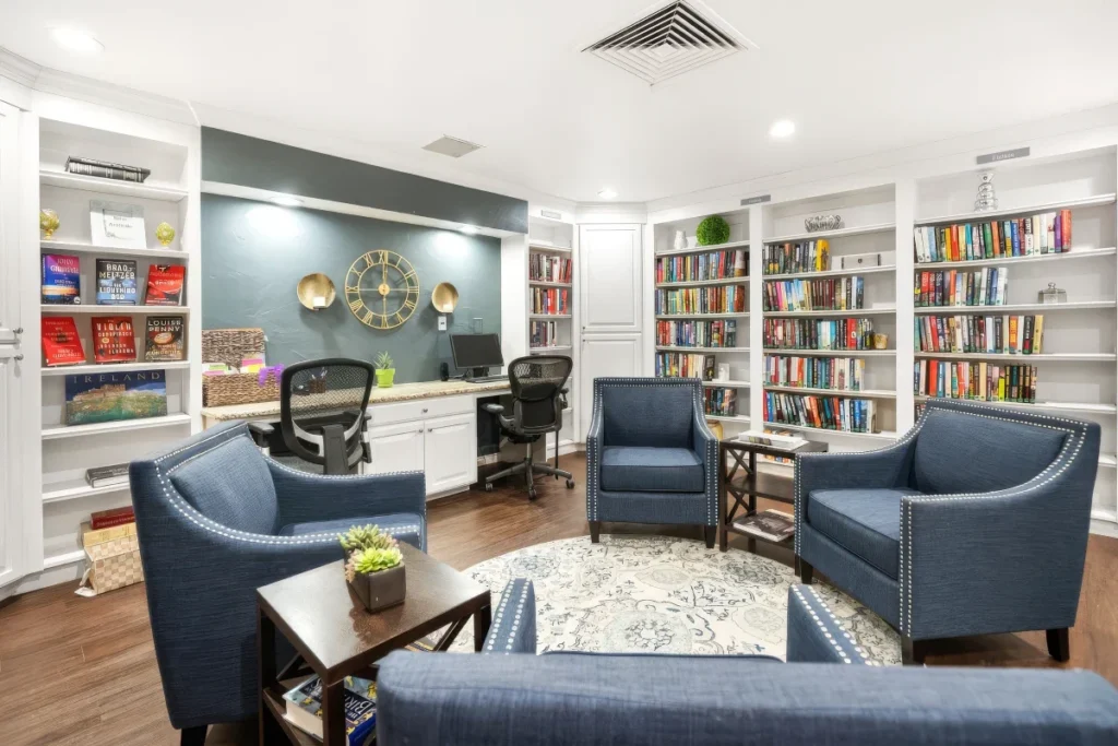 Library with built-in bookshelves, blue armchairs, a desk and a patterned rug