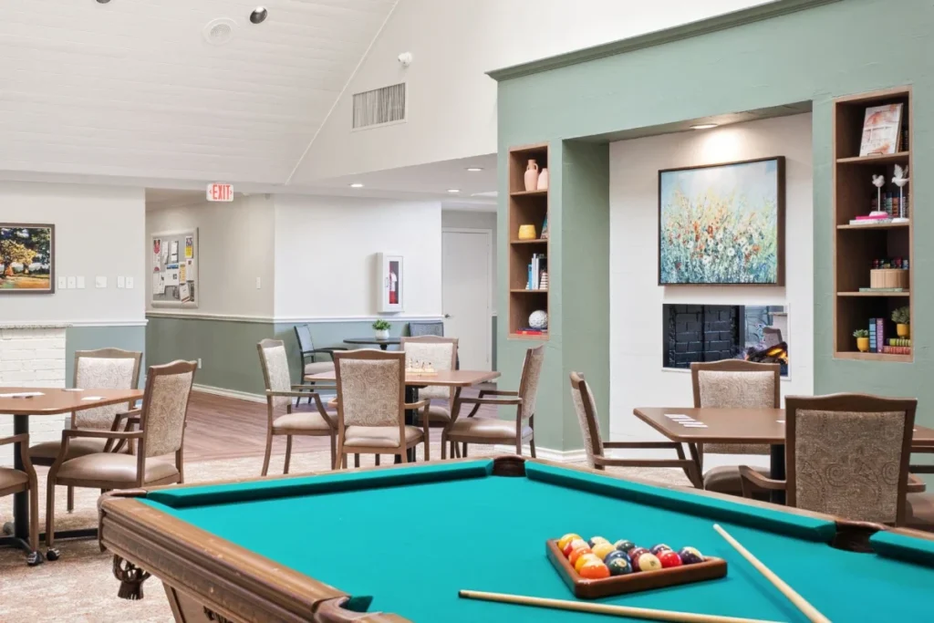 Game room with a pool table and dining tables, with built-in shelves and framed art