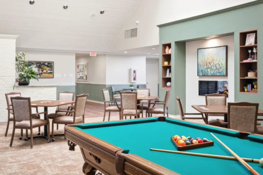 Game room with a pool table set up with billiard balls, and tables and chairs beyond