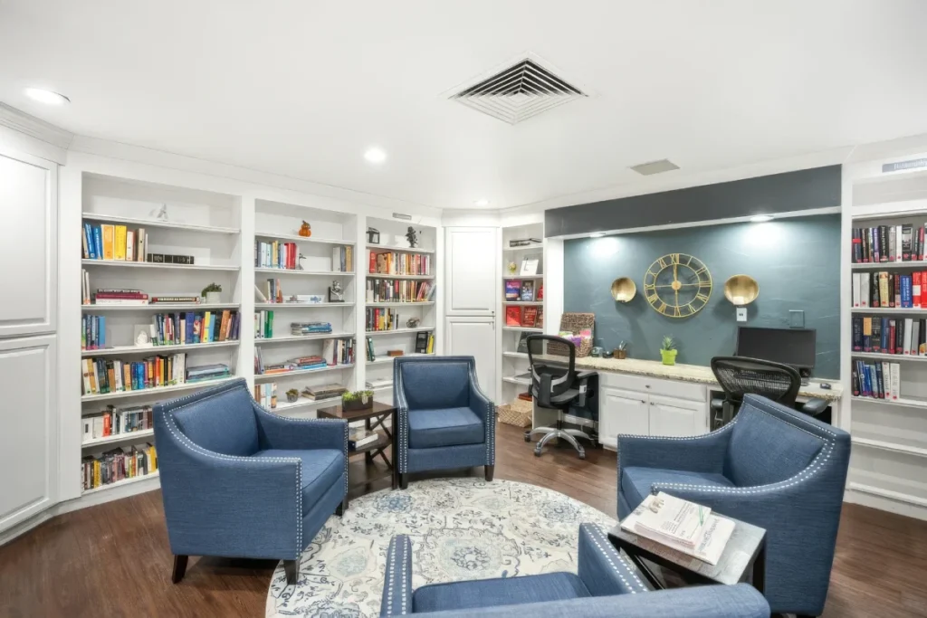 Library room with built-in bookshelves, blue armchairs and a computer desk