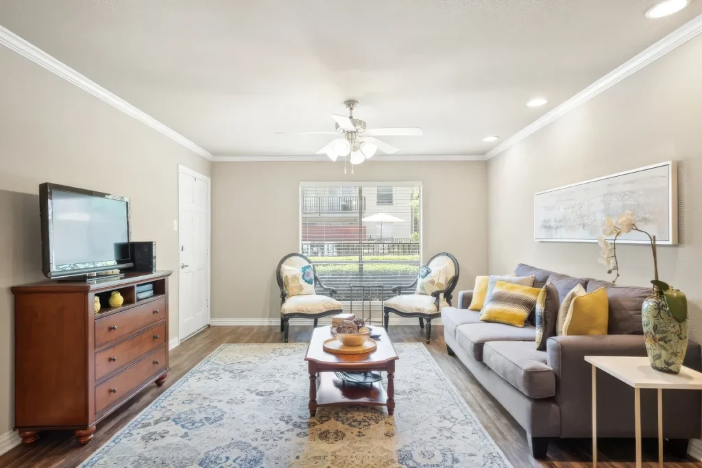 Living room with a gray sofa, a TV on a wood dresser and a coffee table, under a ceiling fan