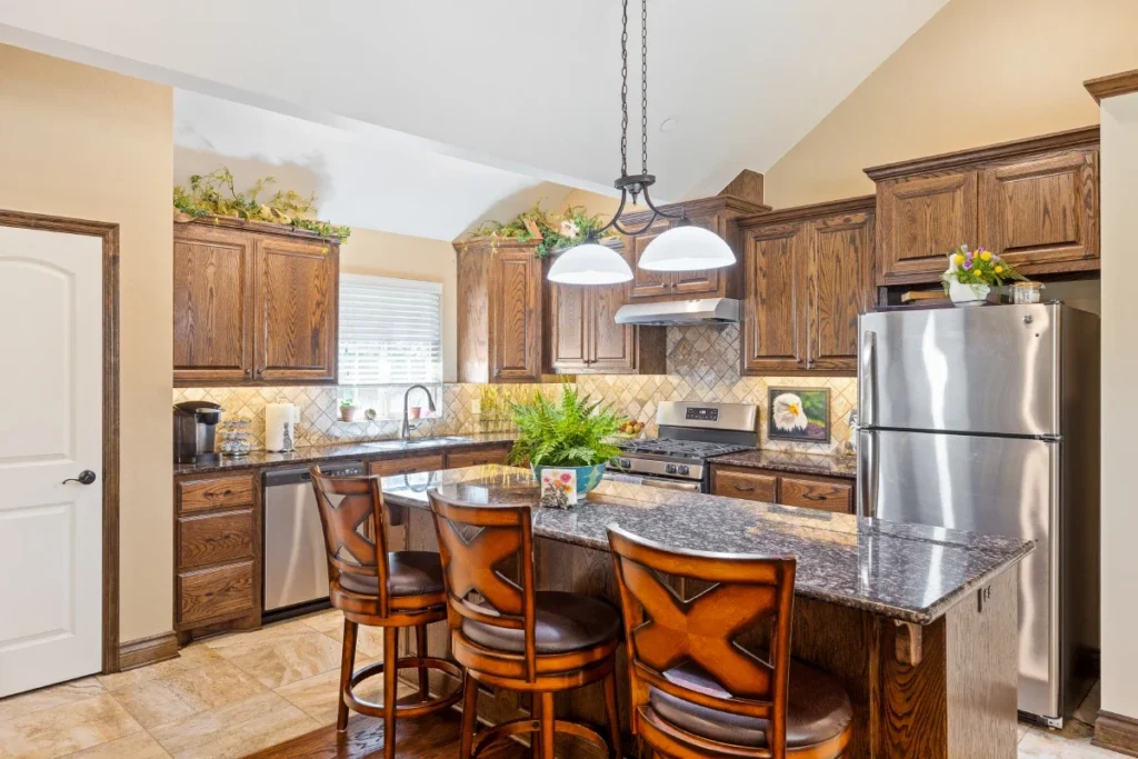 Kitchen with wooden cabinets, a granite island with bar stools and stainless steel appliances