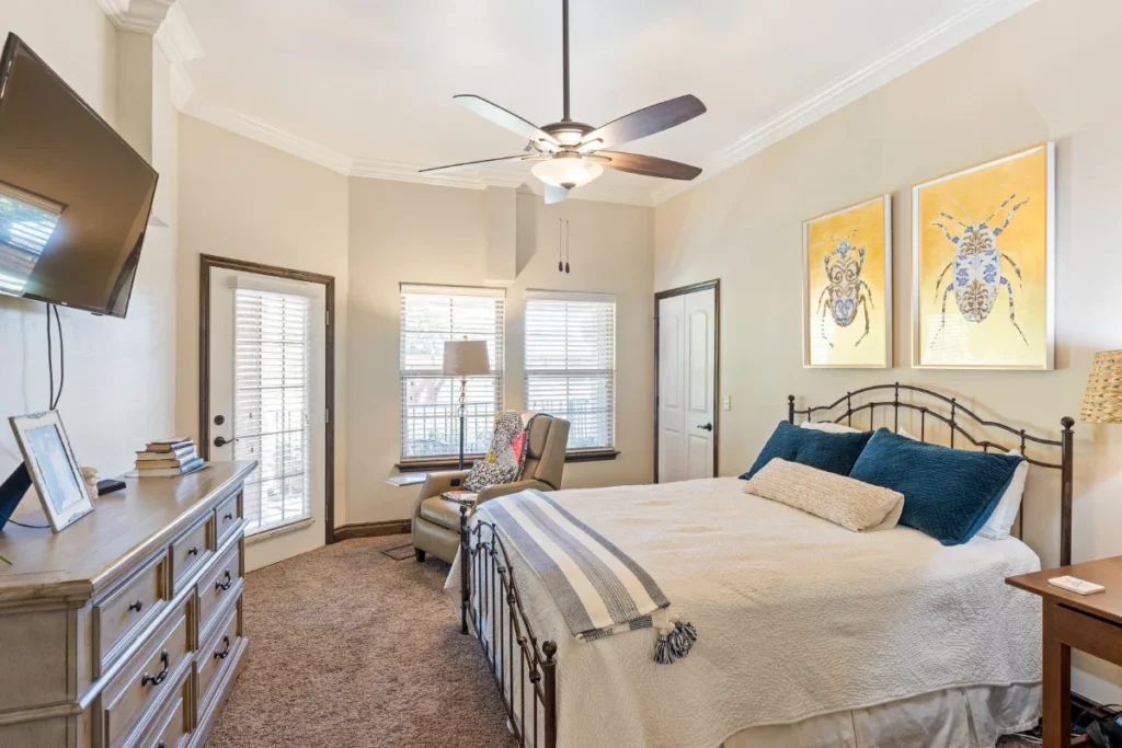 Bedroom with a wrought-iron bed, a dresser, a ceiling fan and a wall-mounted TV