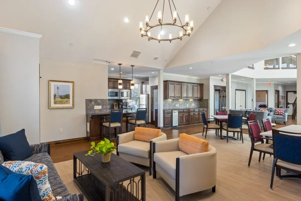 Mon Abri lounge with a sofa, armchairs and a chandelier, with an open kitchen beyond