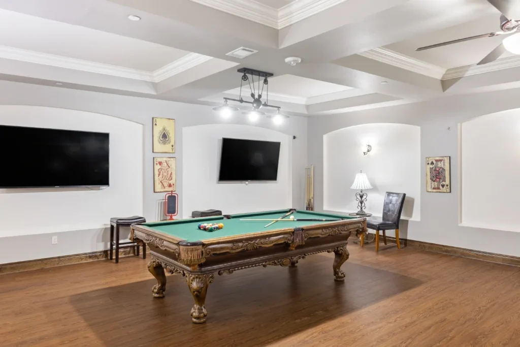 Mon Abri game room with a pool table, two wall-mounted TVs and a coffered ceiling