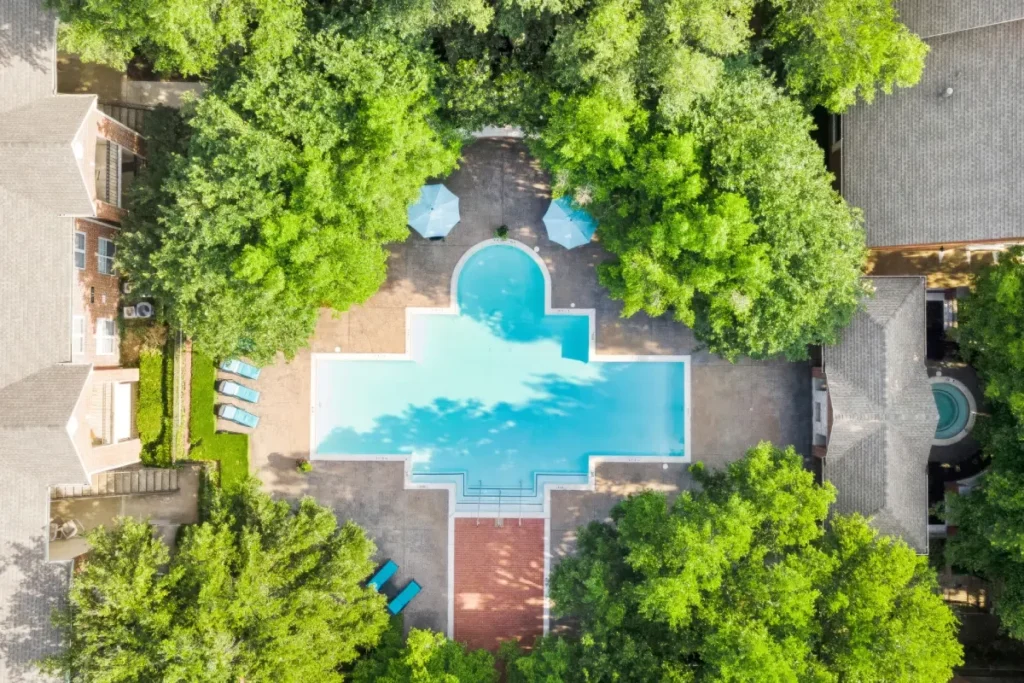 Aerial view looking down at a small pool and patterned deck surrounded by trees