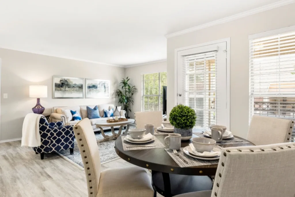 Apartment living and dining area with a round dining table set for four, a navy accent chair and a sofa beyond