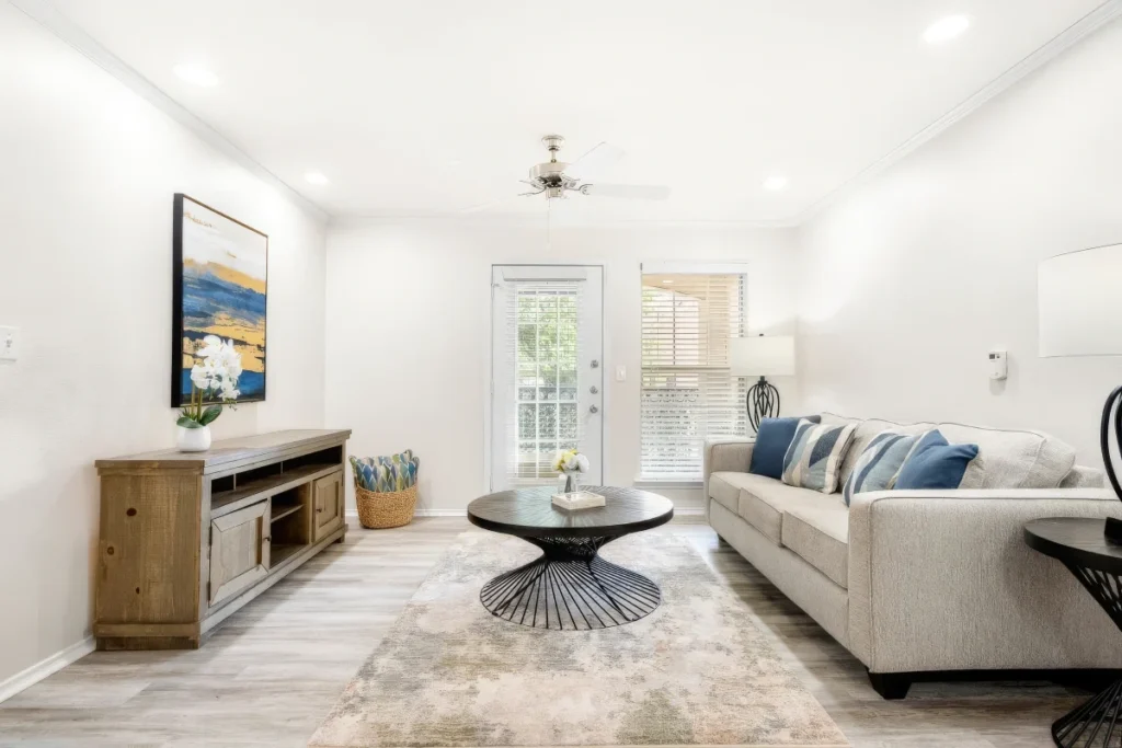 Apartment living room with a white sofa, a wood media console and a round coffee table beside a French door