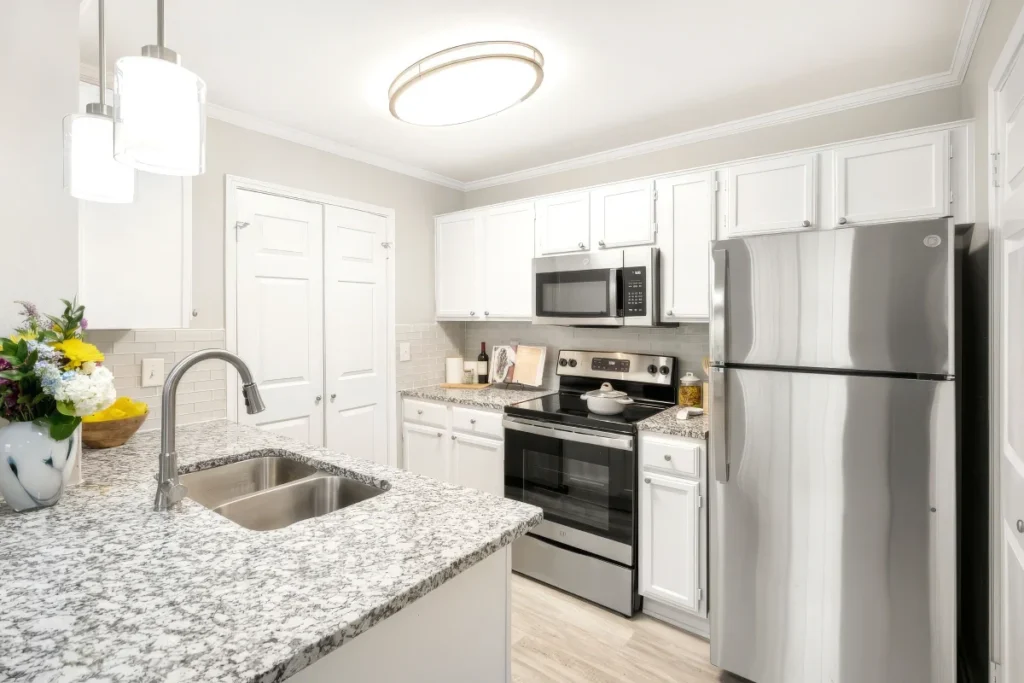 Kitchen with white cabinets, granite countertops, stainless steel appliances and a bouquet of flowers