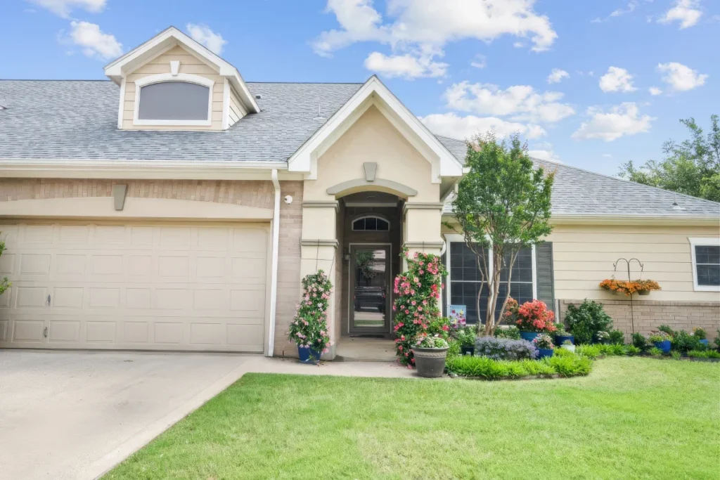 Single-story home with an arched entry, a garage door and a landscaped front lawn under a blue sky