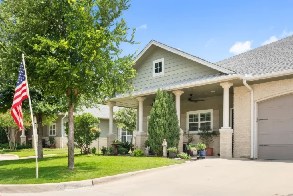 Single-story home with a covered porch, an American flag and a green lawn