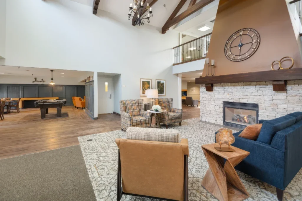 Open lounge with a fireplace, a navy sofa and seating areas, with a pool table in the background