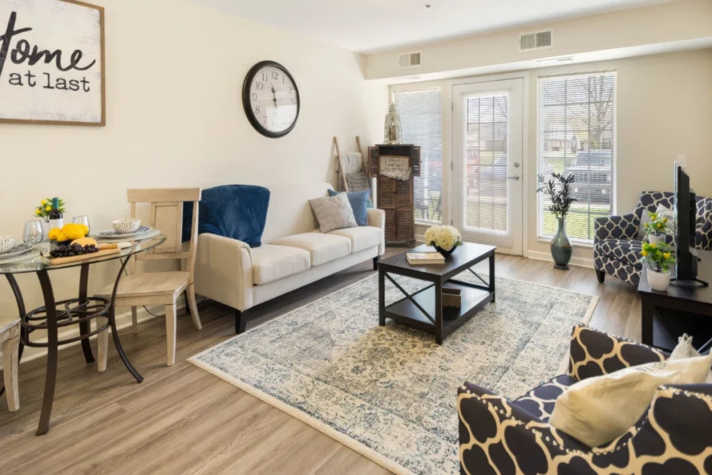 Apartment living area with a sofa, patterned armchairs, a coffee table and French doors, and a small dining table