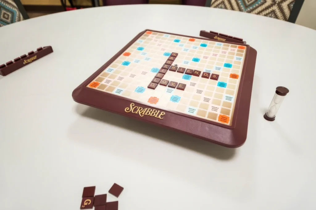 Word-tile board game with an hourglass timer on a white table
