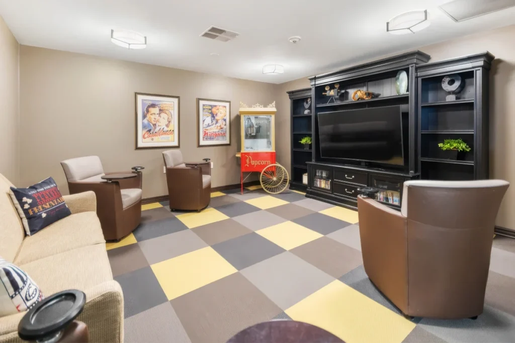 Lounge with a large entertainment center, leather armchairs, a sofa and a checkered floor, with a small popcorn cart