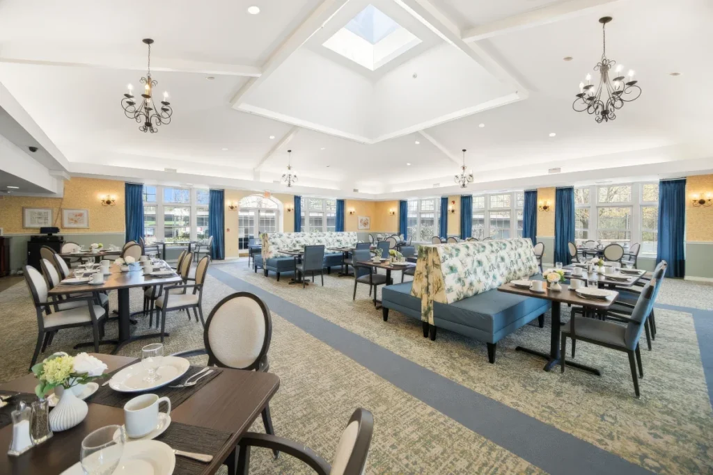 Dining room with set tables, banquette seating and chandeliers under a skylight and coffered ceiling