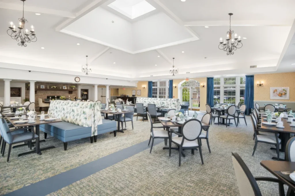 Wide view of a dining room with round tables, blue banquettes and chandeliers