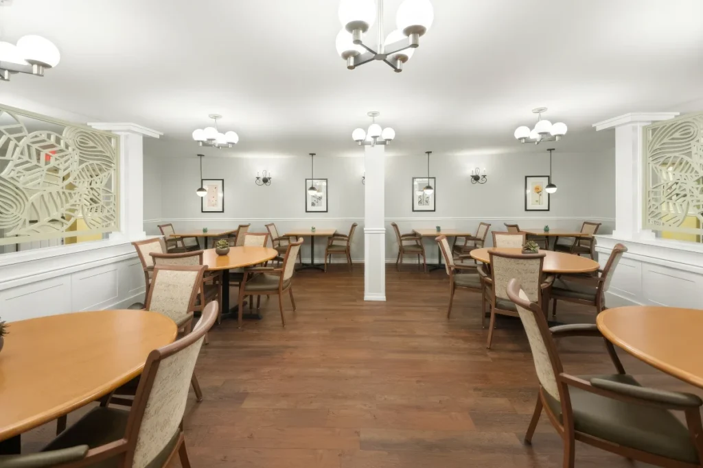 Dining room with round wooden tables and chairs, framed art on the walls and ceiling pendant lights