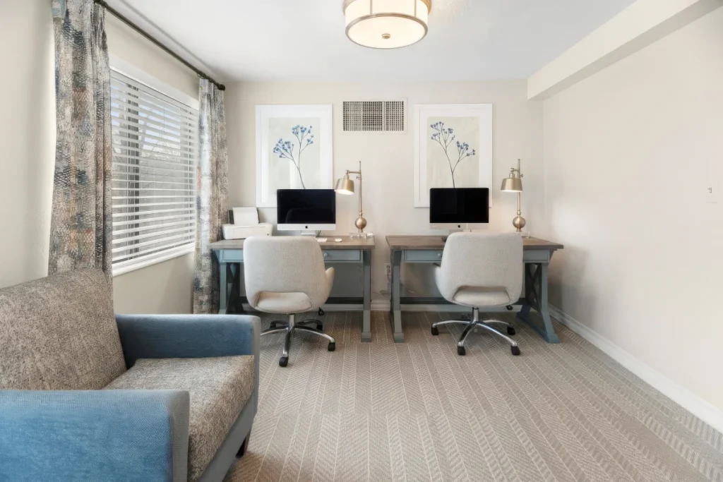 Computer room with two desks with computers, office chairs and a blue sofa