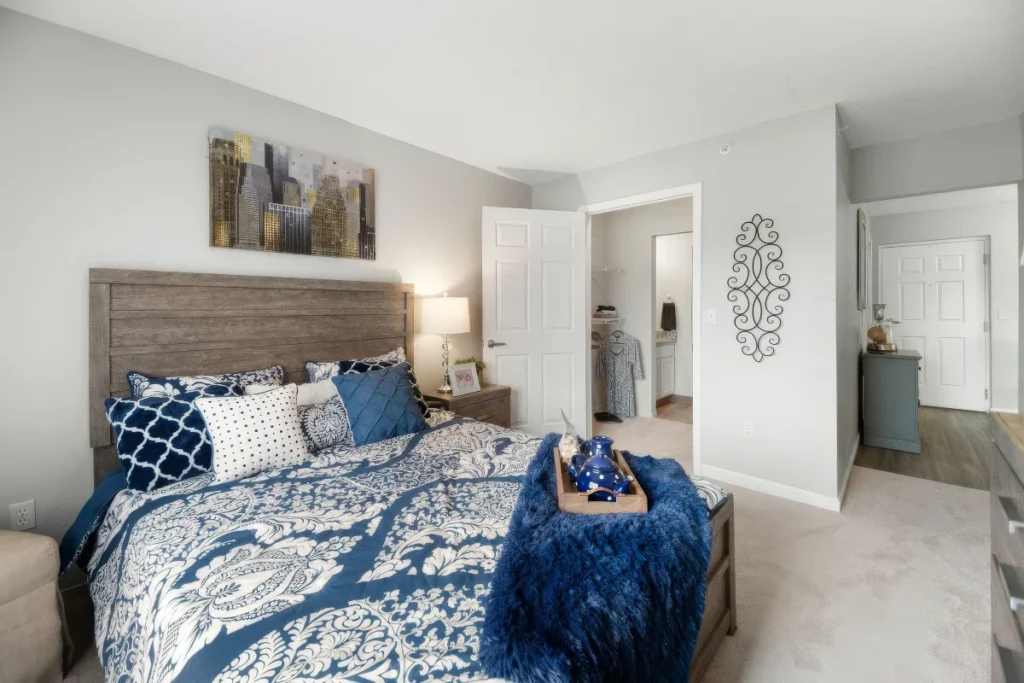 Bedroom with a gray headboard, navy and white patterned bedding and a blue throw