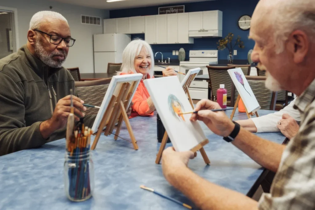 Older adults painting on small tabletop easels at an art table