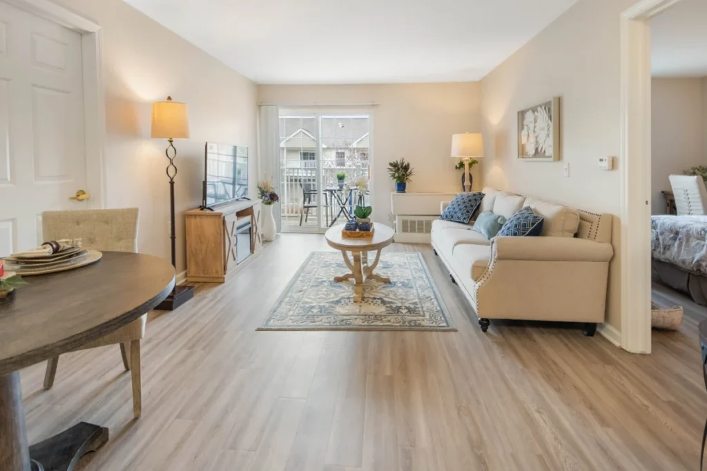 Apartment living room with a beige sofa and wood floors, with a dining table in the foreground