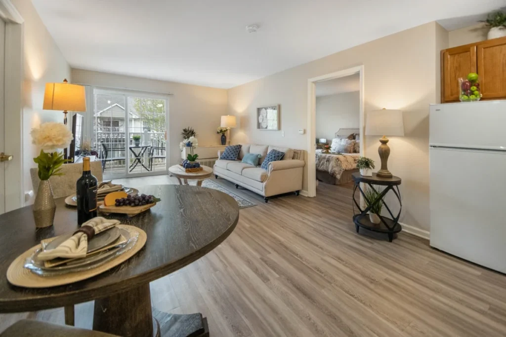 Apartment living and dining area with a round table set with place settings, a sofa beyond and a refrigerator