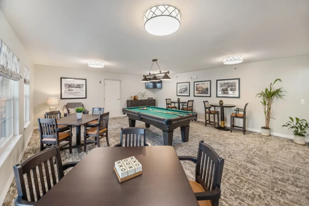 Game room with a pool table, tables and chairs, and a game box on a table in the foreground