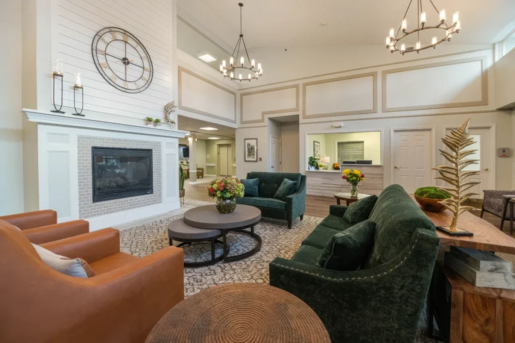 Open lounge with a fireplace and TV, orange armchairs, green sofas and chandeliers