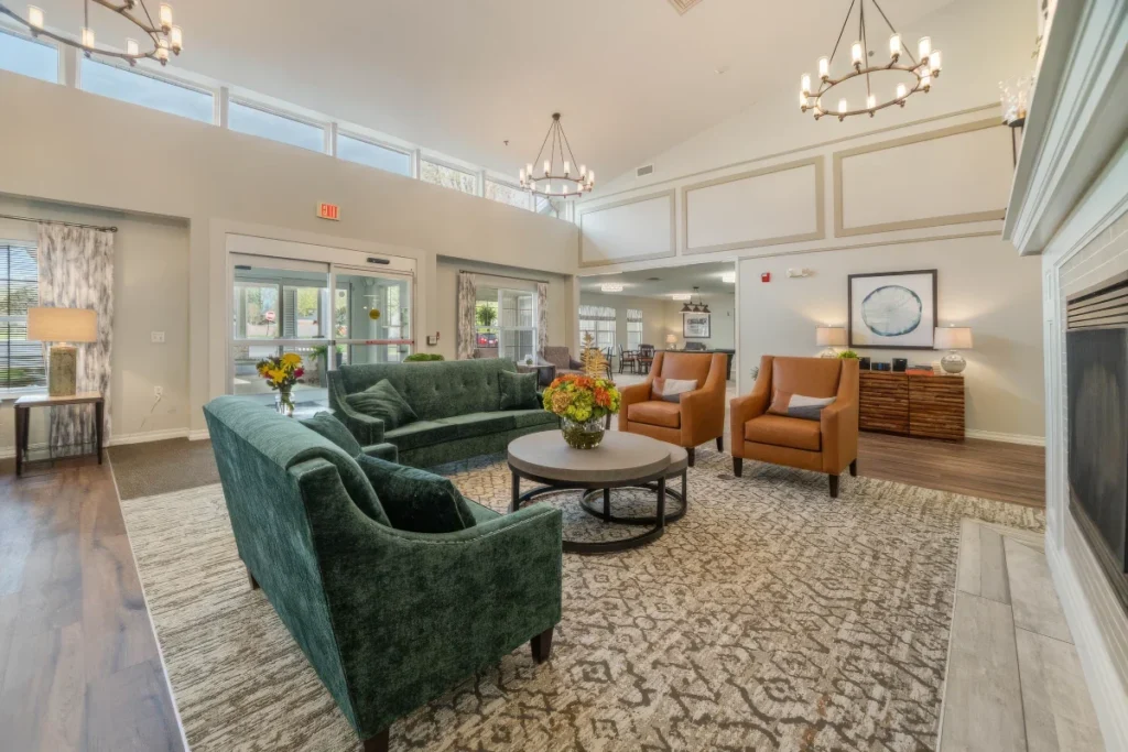 Lounge with green sofas, orange armchairs and a chandelier under a vaulted ceiling