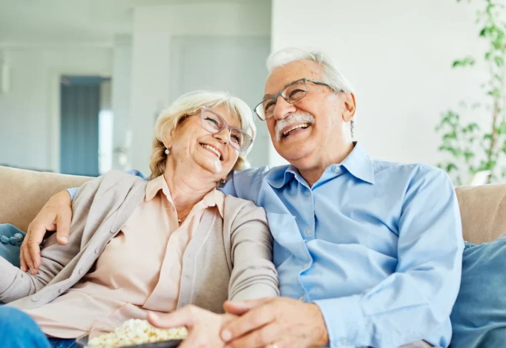Older couple laughing together on a sofa