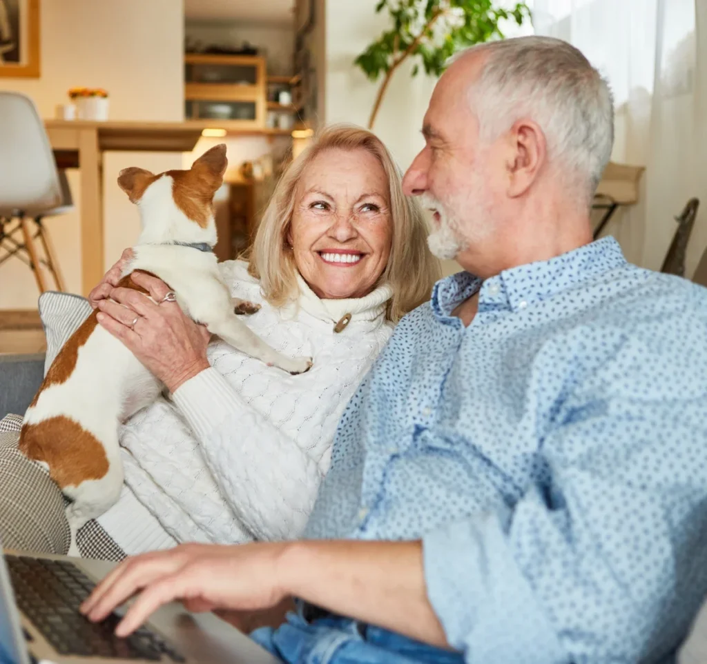 Smiling older couple relaxing on a couch with a small dog