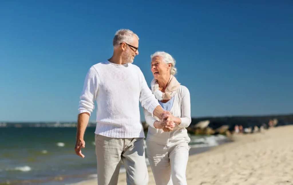 Older couple walking hand in hand along a sandy beach