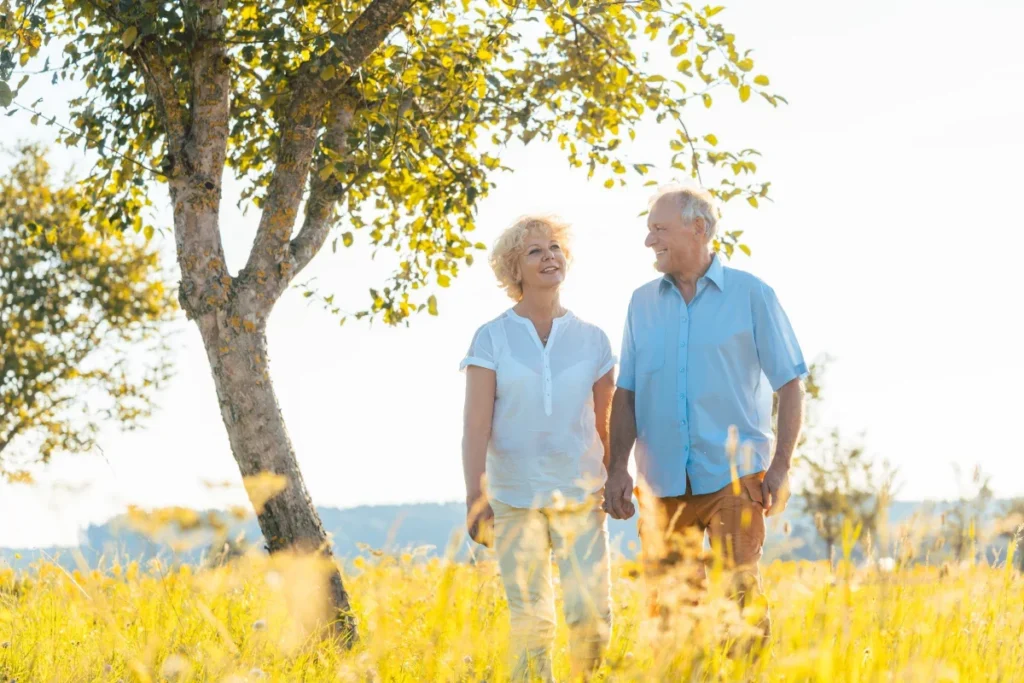 Older couple walking through a golden field in warm evening light