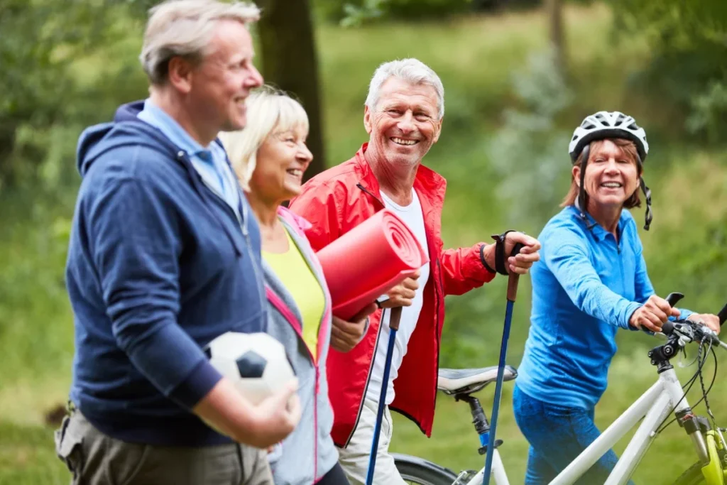 Group of active older adults outdoors, with a bicycle, walking poles and a soccer ball