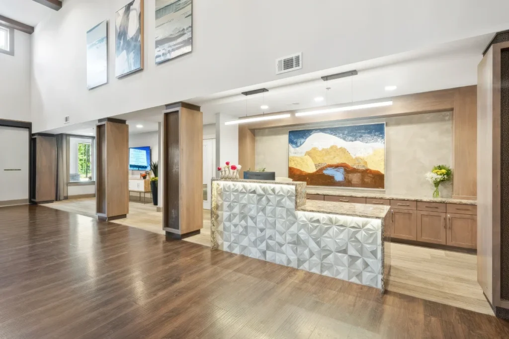 Lobby with a stone-fronted reception desk, wood floors and a colorful painting on the wall behind it