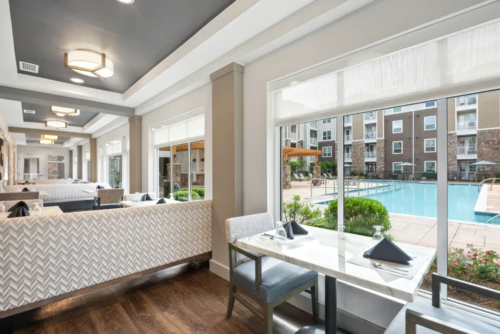 Reception area with a desk and seating, and large windows overlooking a courtyard pool