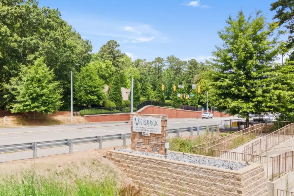 Entrance monument sign beside a road, surrounded by trees and landscaping