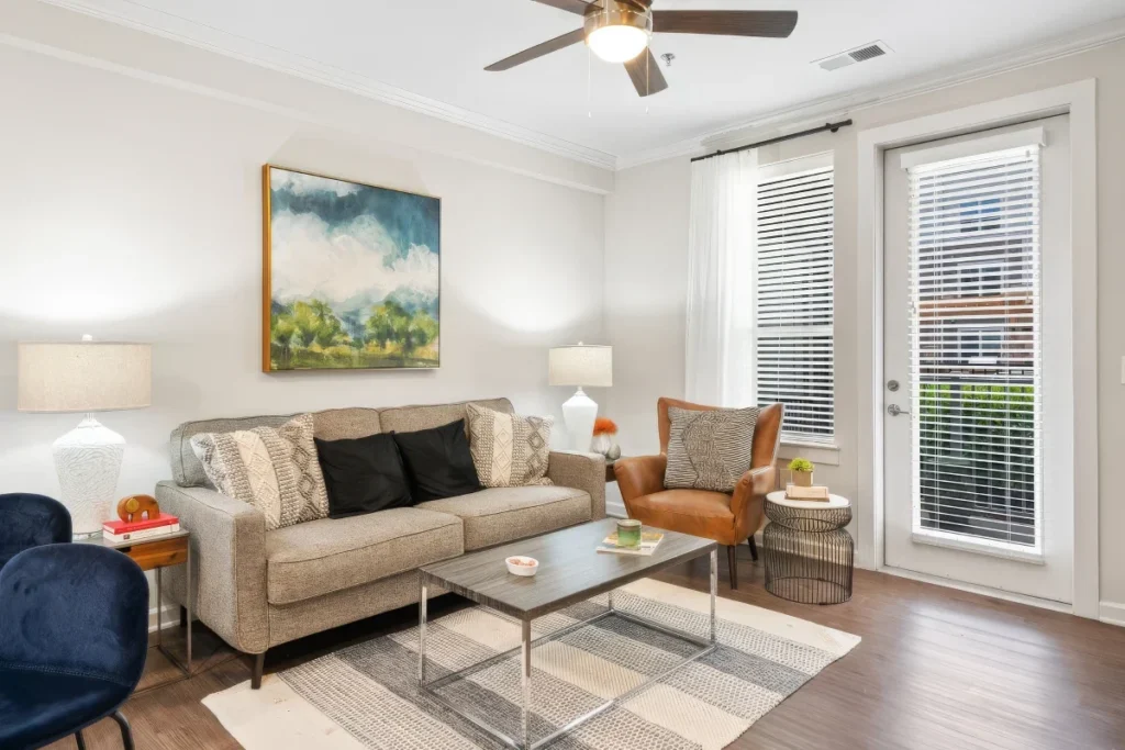 Apartment living room with a beige sofa, an orange leather chair, a coffee table and a balcony door