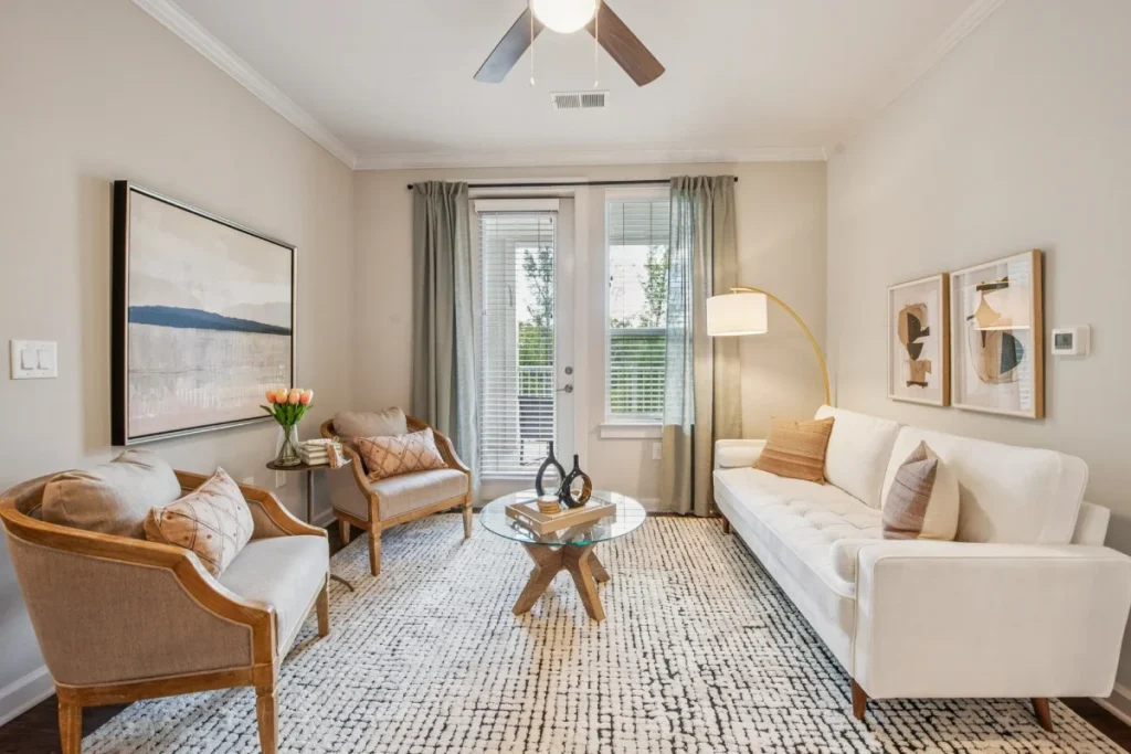 Apartment living room with a white sofa, wicker armchairs, a round coffee table and large abstract art