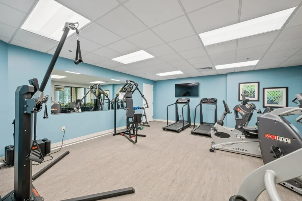 Fitness room with a cable machine, treadmills and a stationary bike against blue walls