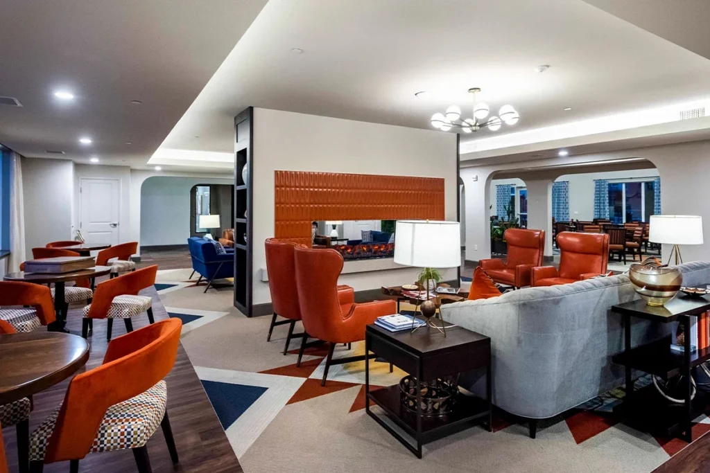 Open lounge with a gray sofa, orange armchairs and a fireplace