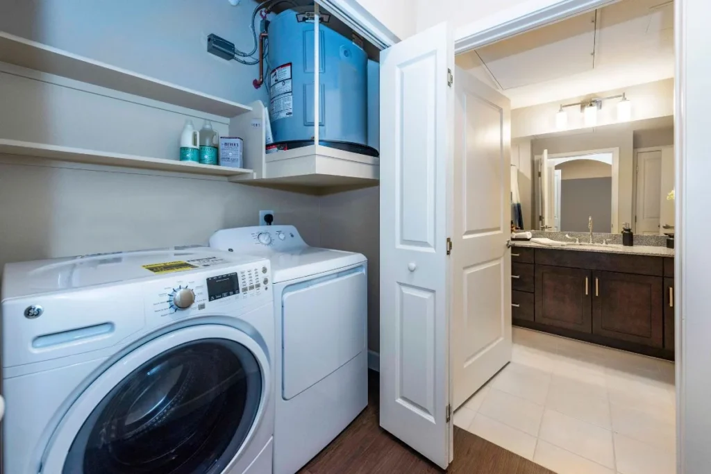 Laundry closet with a washer and dryer, and a bathroom visible through a doorway