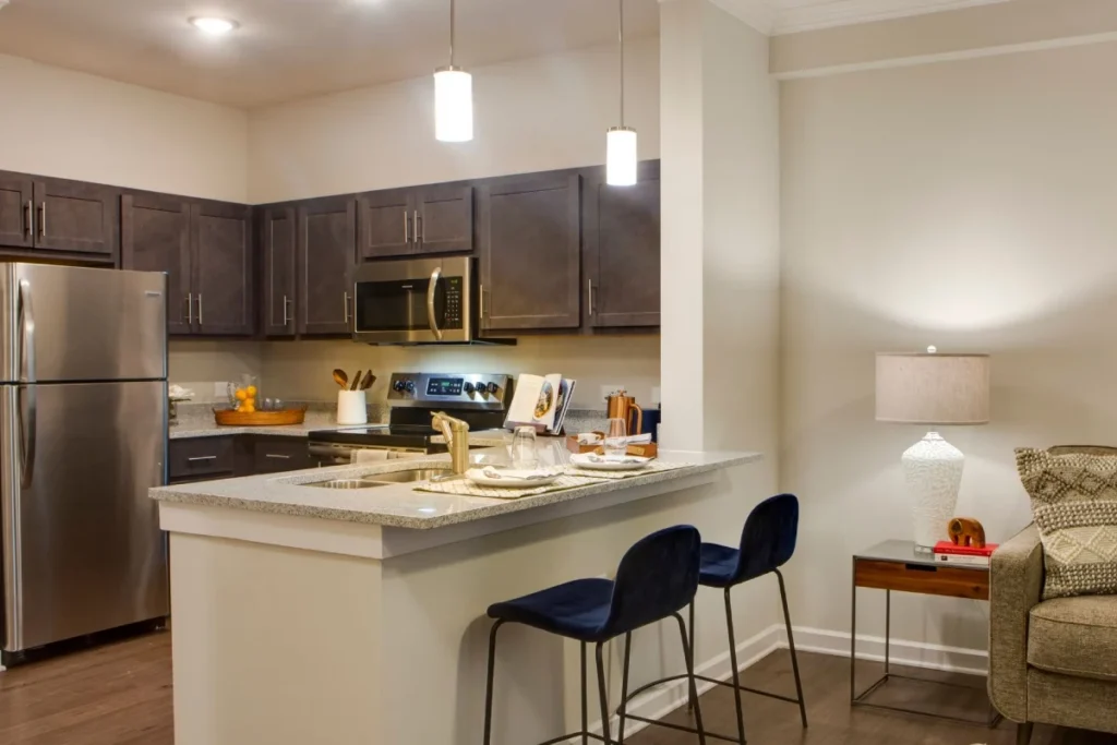 Kitchen with dark cabinets, a stainless steel refrigerator and a breakfast bar with two dark blue stools