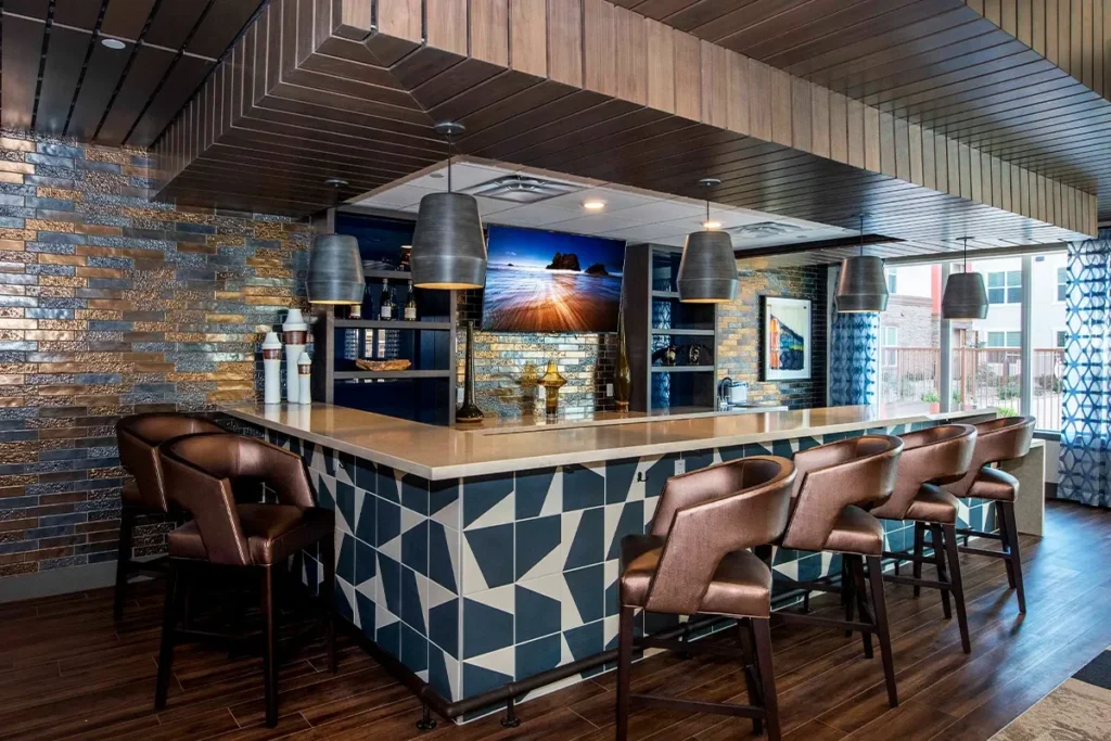 Bar area with a patterned tile counter, leather stools and hanging pendant lights