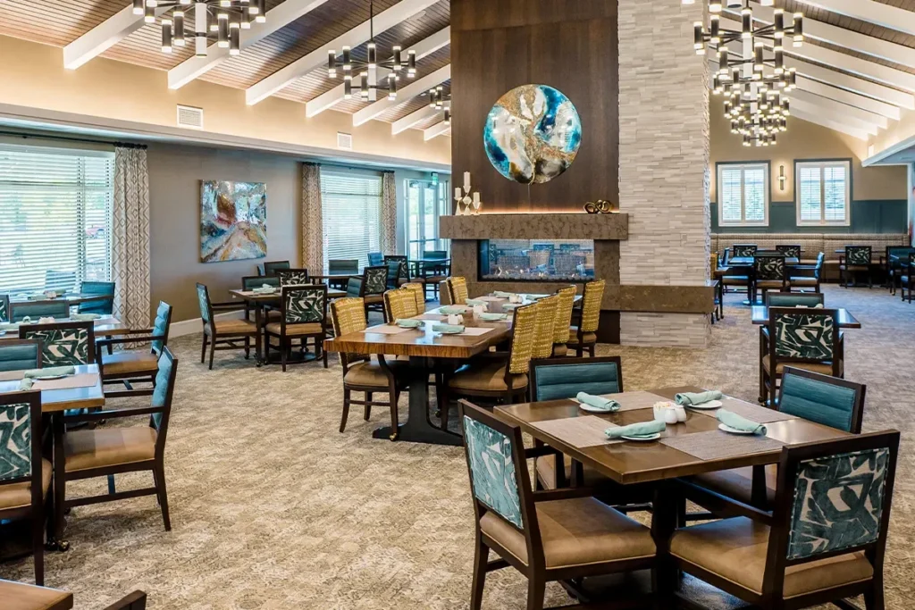 Bright dining room with wooden tables, upholstered chairs and pendant lighting under a beamed ceiling
